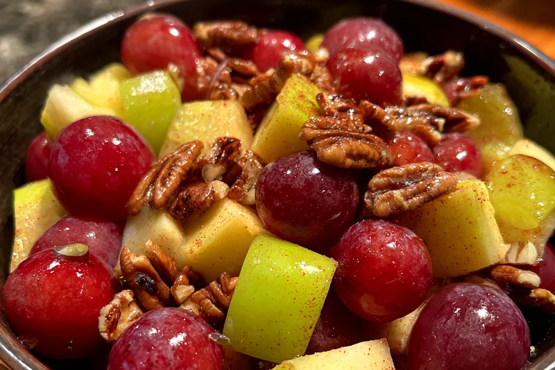 A chef gently mixing the apple and grape mixture for Cinnamon Apple Grape Delight.